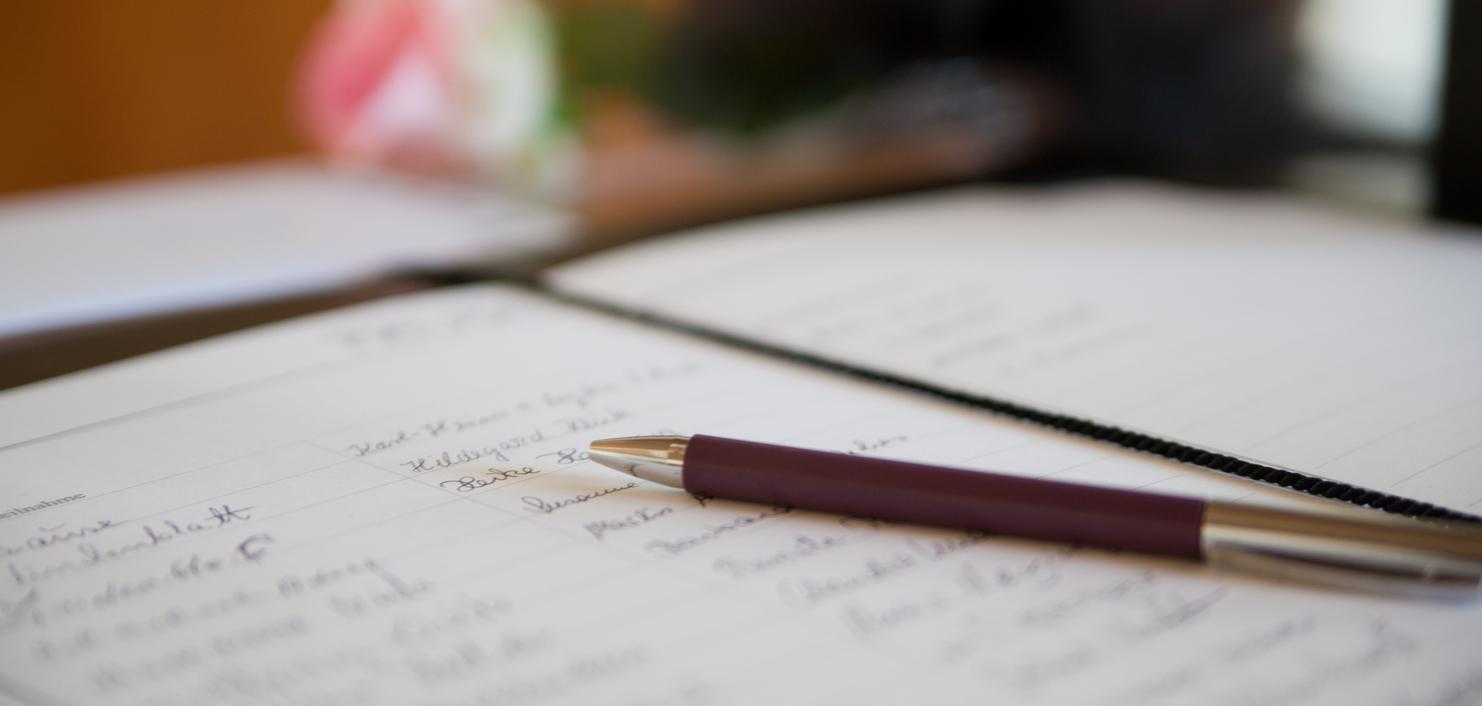 Nahaufnahme eines offenen Notizbuchs mit handschriftlichen Notizen und einem Kugelschreiber auf einem Tisch.